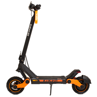 An electric scooter with black and orange color scheme, featuring a large battery and pneumatic wheels, standing upright.